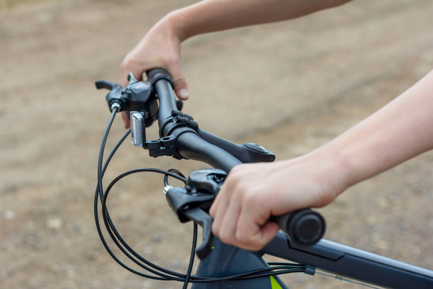 Primer plano de las manos de un adolescente en el manillar de una bicicleta
. - Foto, Imagen