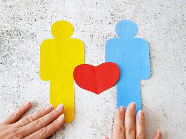Duas pessoas assinam com símbolo de coração de papel colocado à mão no fundo de madeira, conceito lgbt
 - Foto, Imagem