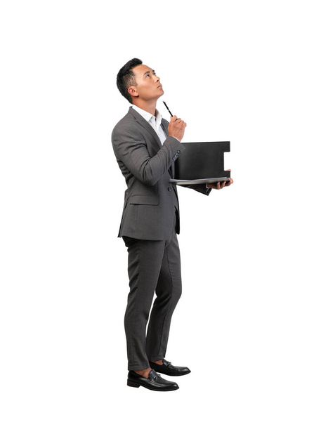 Isolated full length side portrait of thoughtful young Asian businessman with clipboard. Concept of management, paperwork and planning - Foto, immagini