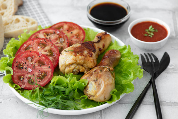 crispy fried chicken drumsticks with fresh tomatoes - Foto, afbeelding
