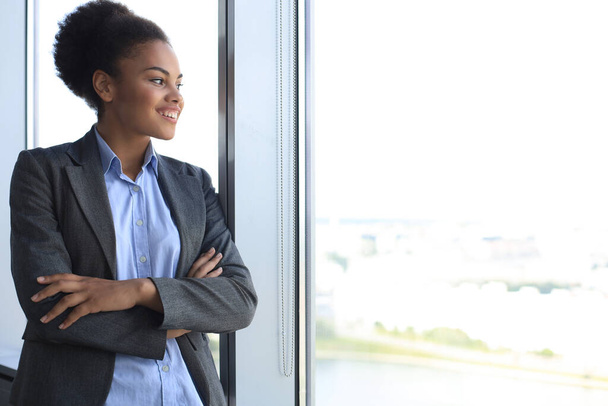Attractive african american business woman smiling while standing in the office - Foto, Bild