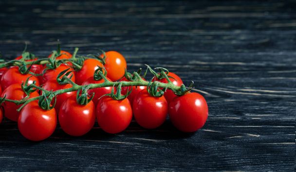 Tomates cherry en la mesa de madera oscura. Jugosas verduras maduras sobre un fondo negro. Alimentación saludable. comida vegetariana
 - Foto, imagen