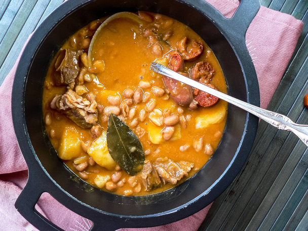 黒い鉄鍋にチョリソ、ジャガイモ、豚肋骨とベイリーフとスペインの典型的な豆。 - 写真・画像
