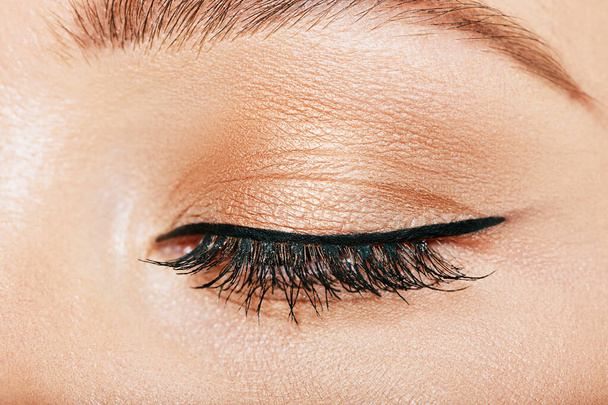 Closeup of beautiful woman eye with makeup, soft golden eyeshadow and black eyelinear - Photo, Image