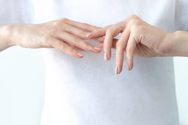 Vrouwelijke handen met zacht beige manicure. - Foto, afbeelding