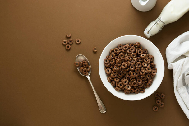 Chocolate cereal rings in bowl brown background. Breakfast for kind. Copy space. - Fotó, kép