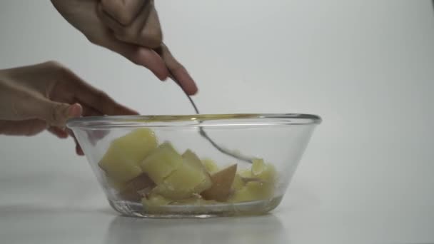 Uzavření procesu výroby bramborové kaše. Akce. Žena ruce dělat bramborovou kaši se stříbrnou vidličkou v čiré skleněné misce v kuchyni. - Záběry, video