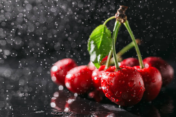 Cerejas vermelhas frescas com gotas de água no fundo escuro, vista de perto. - Foto, Imagem