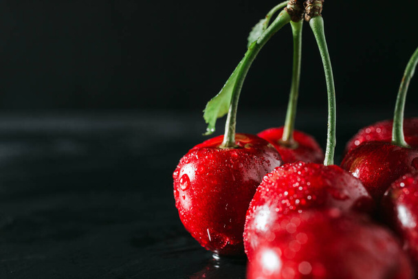 Fresh red cherries with water drops on dark background, close-up view. - Foto, Imagen