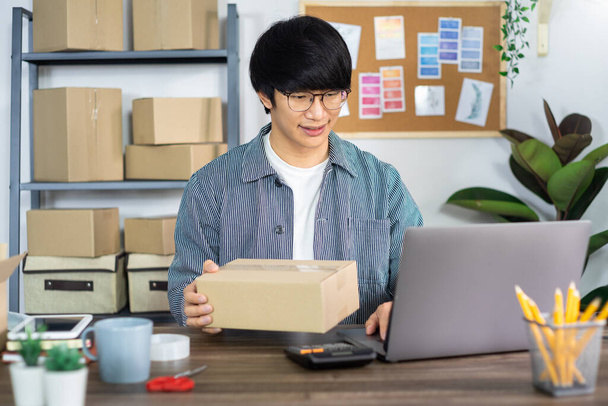 Asian business man startup SME entrepreneur or freelance working in a cardboard box prepares delivery box for customer, Online selling, e-commerce, packaging and shipping concept - Fotoğraf, Görsel