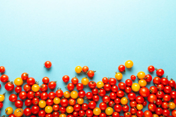 Red and yellow cherry tomatoes on blue background. Fresh bright organic vegetables. Copy space for text. - 写真・画像