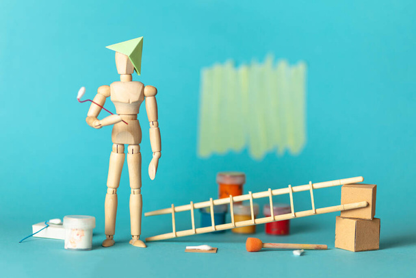 Wooden figure of man paints walls in apartment room, repair and renovation of design and decor. Paint buckets and a step ladder. DIY indoors work. - Fotoğraf, Görsel