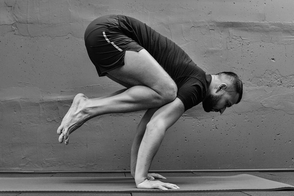 Joven deportista haciendo ejercicio, haciendo yoga de pie de manos. Estudio en gimnasio urbano con fondo gris para espacio de copia. - Foto, imagen