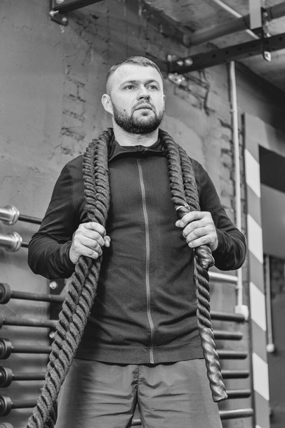 Young man working out with battle ropes at a gym. Close up sport fitness concept. - Zdjęcie, obraz