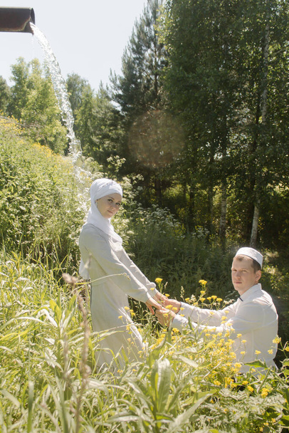 Pareja joven musulmán hombre y mujer en el campo de verano se miran entre sí. Boda tártara musulmana
. - Foto, imagen
