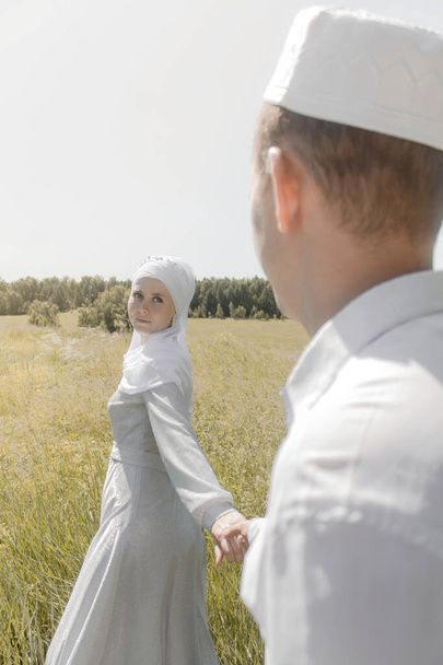 Para młodych muzułmanów na letnim polu patrzy na siebie. Muzułmański ślub tatarski. - Zdjęcie, obraz