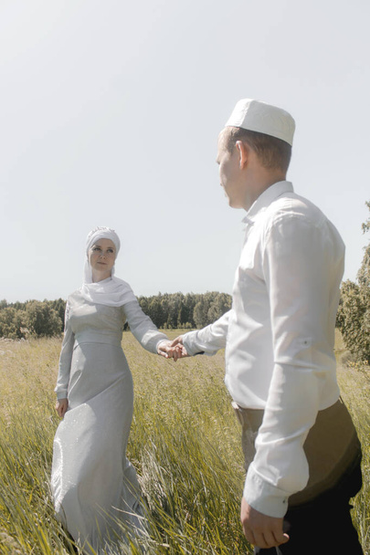 Para młodych muzułmanów na letnim polu patrzy na siebie. Muzułmański ślub tatarski. - Zdjęcie, obraz