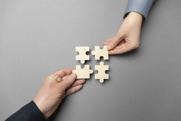 Two hands connect puzzles on a grey background. Cooperation and teamwork in business. Collaboration people for success. - Φωτογραφία, εικόνα
