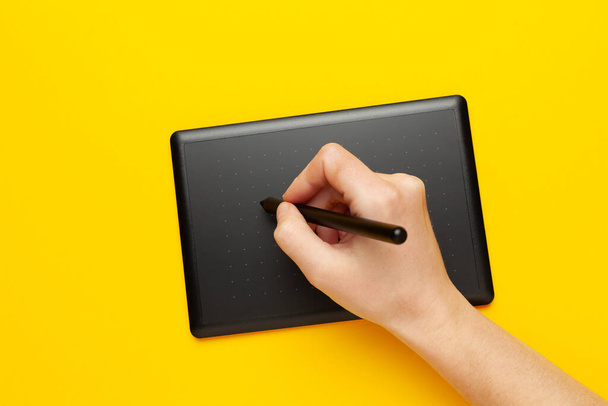 Graphic tablet for drawing and designer hand on yellow background. Creative art, sketch. - Foto, Imagen