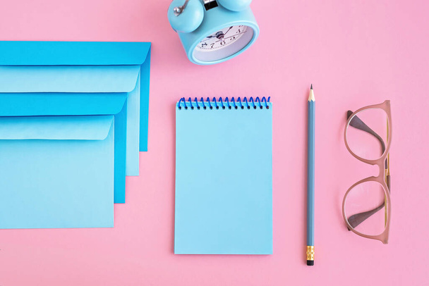 Blue correspondence envelopes, clock and notebook on pink background with copy space. Back to school or work concept. Top view. - Foto, Bild