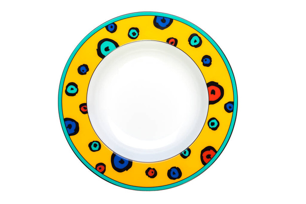 Placa redonda vacía de cerámica amarilla con bordes multicolores brillantes aislados sobre un fondo blanco
 - Foto, Imagen