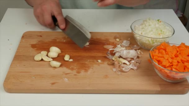 Uomo che taglia l'aglio su un tagliere di legno, primo piano - Filmati, video