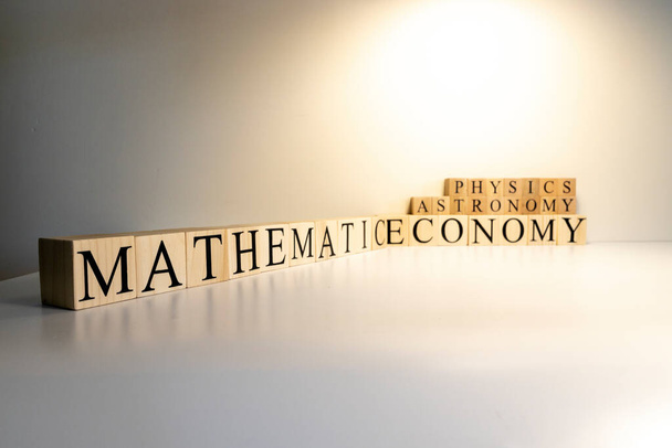 Conceito de educação. Educação e relação matemática. Matemática, astronomia, economia palavras com letras de cubos de madeira
 - Foto, Imagem