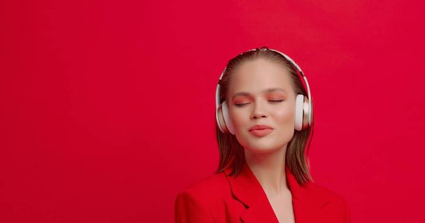 Una hermosa joven con auriculares inalámbricos escucha canciones con buen humor. cartel de música colorido brillante. - Foto, Imagen