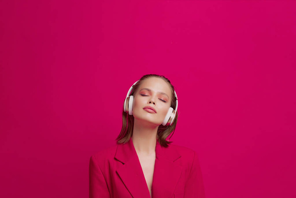 A beautiful young girl in wireless headphones listens to song with a good mood. bright colorful music poster. - Photo, image