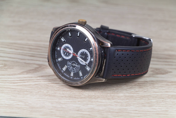 Uhr mit schwarzem Armband auf Holzhintergrund - Foto, Bild