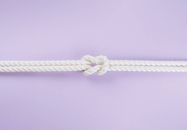 White ship ropes connected by reef knot. On light purple background - 写真・画像