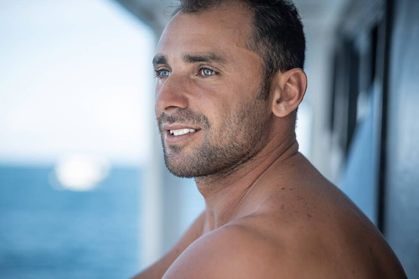 Portrait of handsome man with white teeths smile, blue eyes, surfer and blue ocean on background - Foto, immagini
