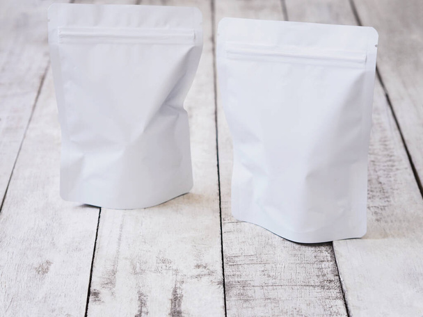 Weiße Reißverschlusstasche für Lebensmittelverpackungen. Leere Reißverschlusspackung auf Holztisch. - Foto, Bild