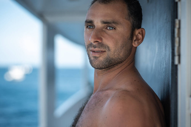 Portrait of handsome man with white teeths smile, blue eyes, surfer and blue ocean on background - Foto, Imagen