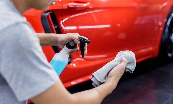 Car service worker polishing car wheels with microfiber cloth. - Фото, изображение