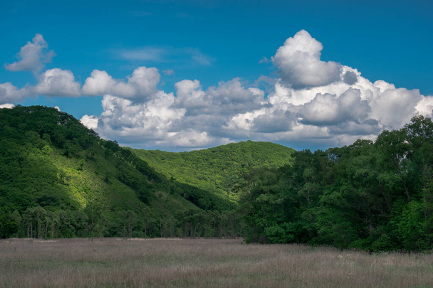 Letní krajina se zelenými loukami a kopci a modrá obloha s mraky - Fotografie, Obrázek