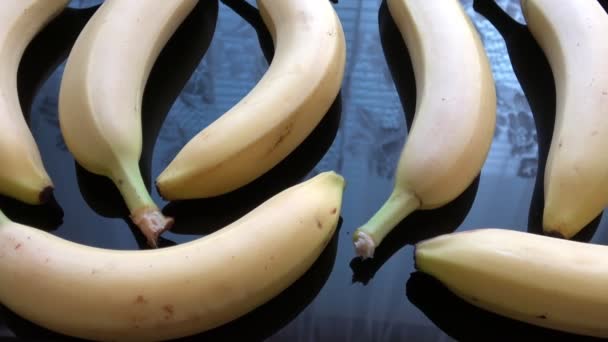 Gele hele bananen op een zwart oppervlakglas - Video