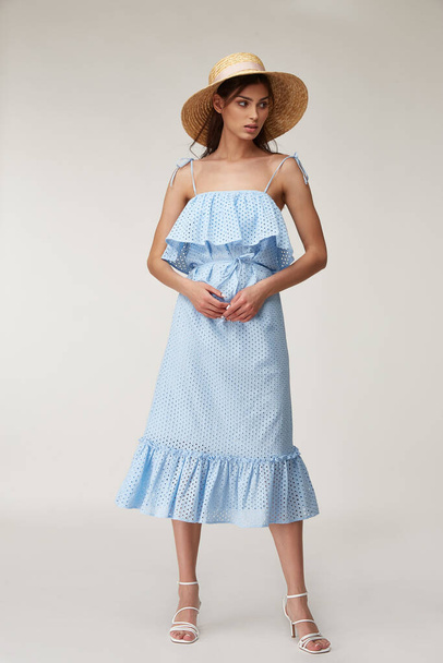 Woman beautiful face natural make up brunette hair tanned skin body wear fashion summer collection organic cotton lace long blue dress style for romantic date walk, accessory and shoes sandals hat. - 写真・画像