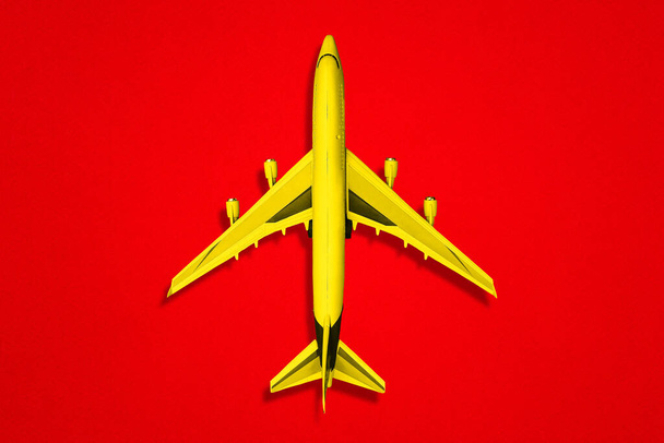 Κίτρινο αεροπλάνο σε κόκκινο φόντο. Μια κορυφαία άποψη μιας επίπεδης διάταξης - Φωτογραφία, εικόνα