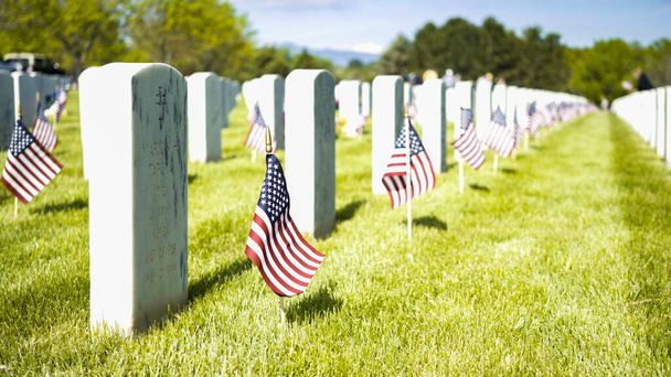 Denver, Colorado, USA-26 mei 2019 - Kleine Amerikaanse vlaggen naast witte marmeren grafstenen op het Fort Logan National Cemetery op Memorial Day. - Foto, afbeelding