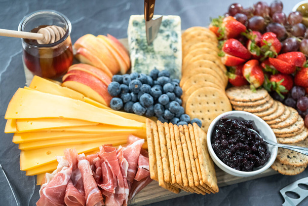 Gurmánský sýr, krekry a ovoce na dřevěné řezací desce sloužily jako předkrm. - Fotografie, Obrázek