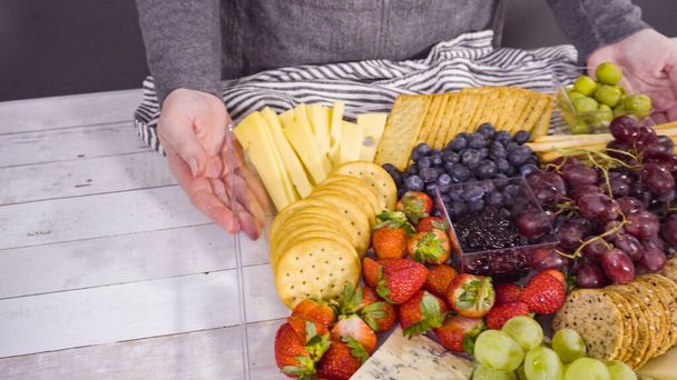 Paso a paso. Organizar bandeja de queso con frutas frescas, queso gourmet y galletas saladas. - Foto, imagen