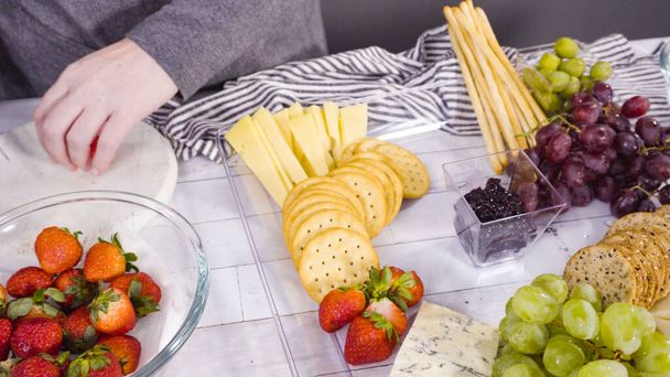 Pas à pas. Disposer un plateau de fromage avec des fruits frais, du fromage gastronomique et des craquelins. - Photo, image