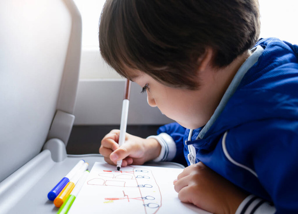 Selektiver Fokus des kleinen Jungen zeichnet mit Buntstift auf weißem Papier, Kind reist mit dem Zug, Kleiner Junge im Schnellzug im Familienurlaub, Unterhaltung für junge Passagiere. - Foto, Bild