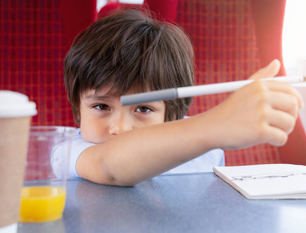 Portré gyerek néz kamera kézben tartott színes toll, gyermek unatkozó arc ül a vonaton, Aranyos fiatal fiú ül az ablak mellett utazik vonattal a nyári napon, Kid és a családi nyaralás koncepció - Fotó, kép