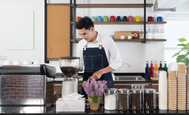 joven asiático hombre utilizando cafetera para elaborar expresso en el café. concepto de barista y cafetería
 - Foto, imagen
