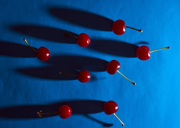 cherry on blue background with shadows. High quality photo - Photo, Image