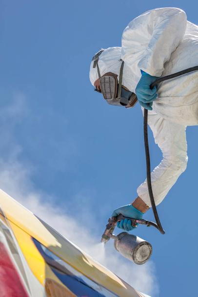 Aircraft painting and sandblasting. Spray painting, airplane wing. Worker in coverall using airbrush. - Photo, Image