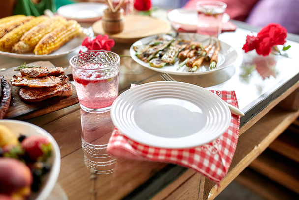 Stół obiadowy z grillem mięsnym, pieczone warzywa, sosy i lemoniada, przystawki różnych porcji na zewnątrz strony stołu - Zdjęcie, obraz