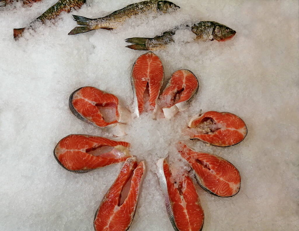 Le bistecche di salmone refrigerate giacciono nel ghiaccio sul bancone di un negozio. Carne di pesce rosso in un supermercato di pesce. Alimentazione sana concetto. - Foto, immagini